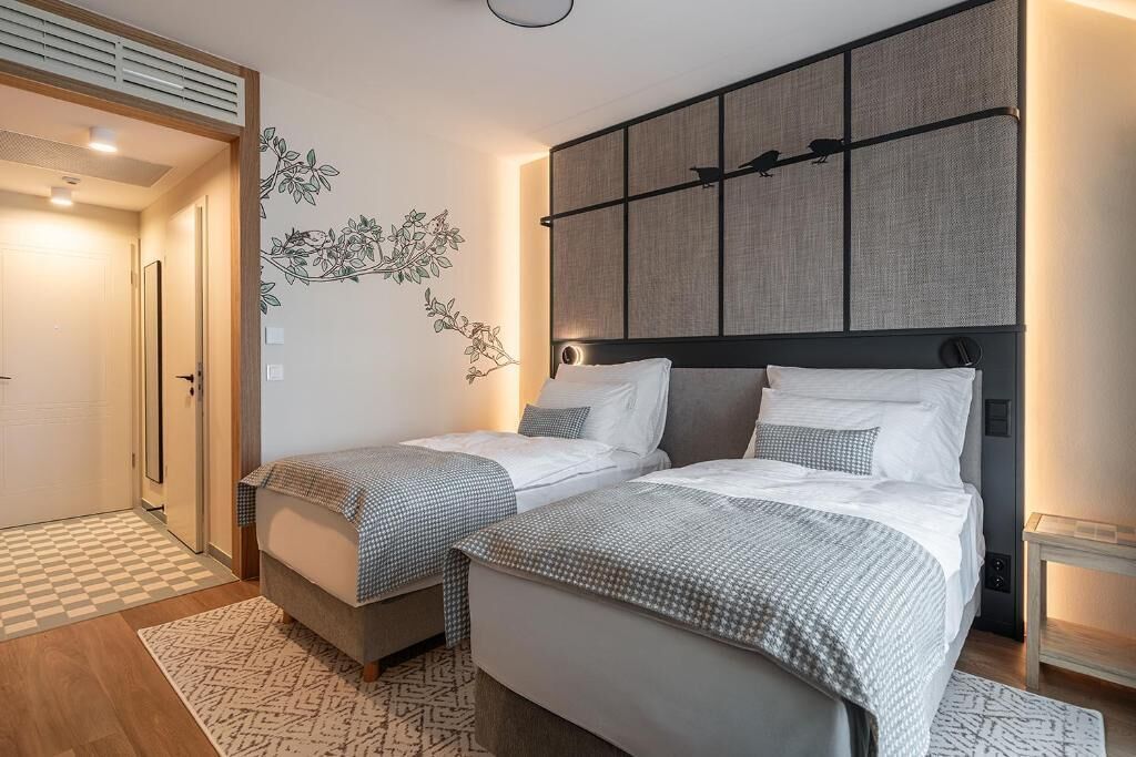 Habitació d'hotel amb dos llits, una finestra gran i una obra d'art penjada a la paret.
