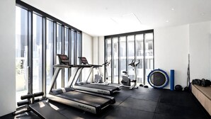 Une salle de sport équipée de tapis de course, de vélos elliptiques et d’un trampoline.