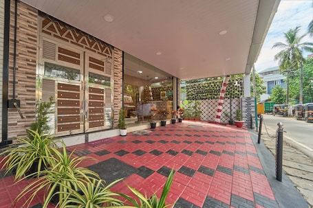 A hotel entrance with a red and black checkered pavement, potted plants, and a covered area with a patterned wall.. Itsy Hotels Salees Enclave - Near Padmanabhaswamy Temple