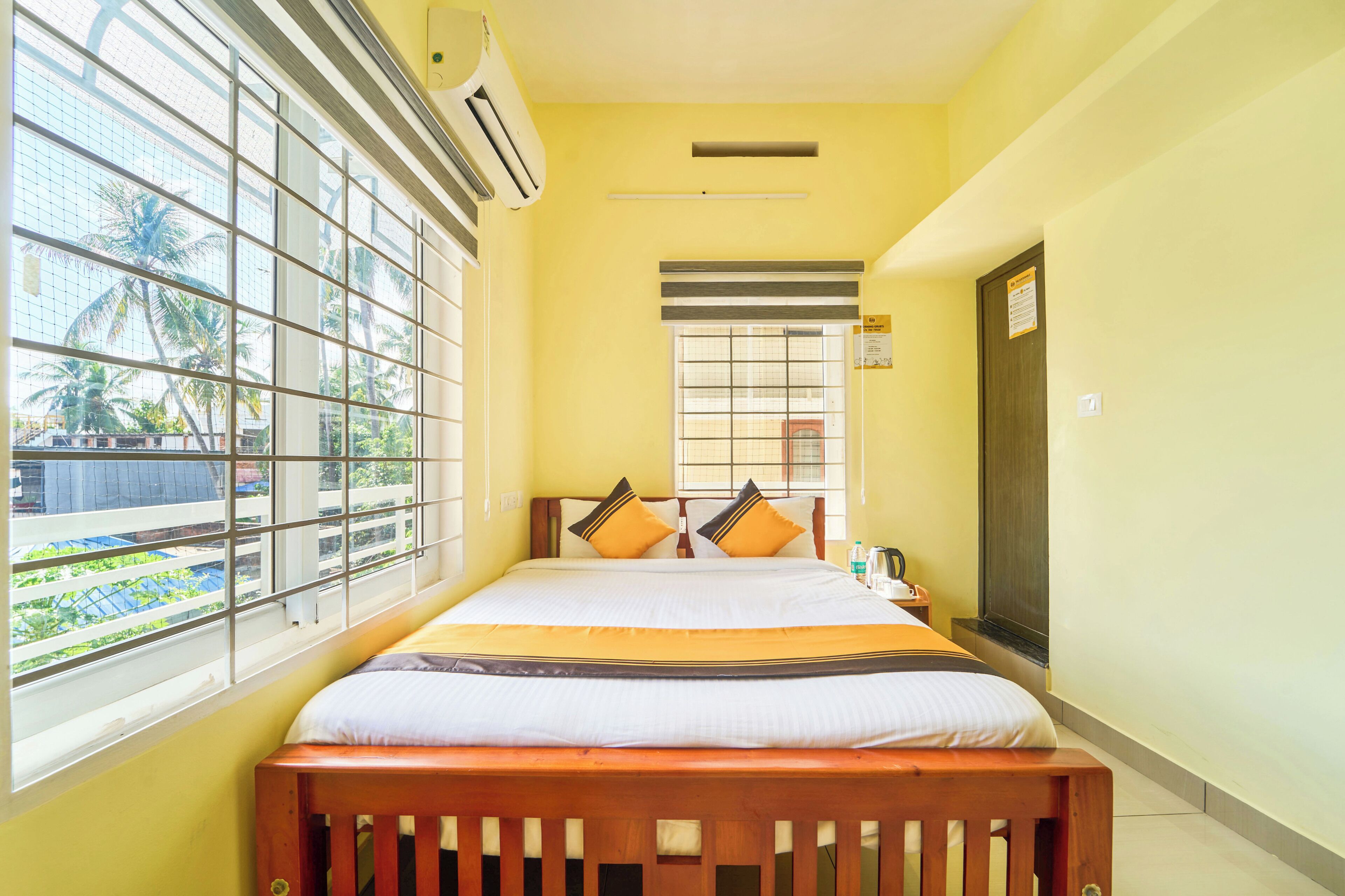 A room with a bed, a window, an air conditioner, and a door.