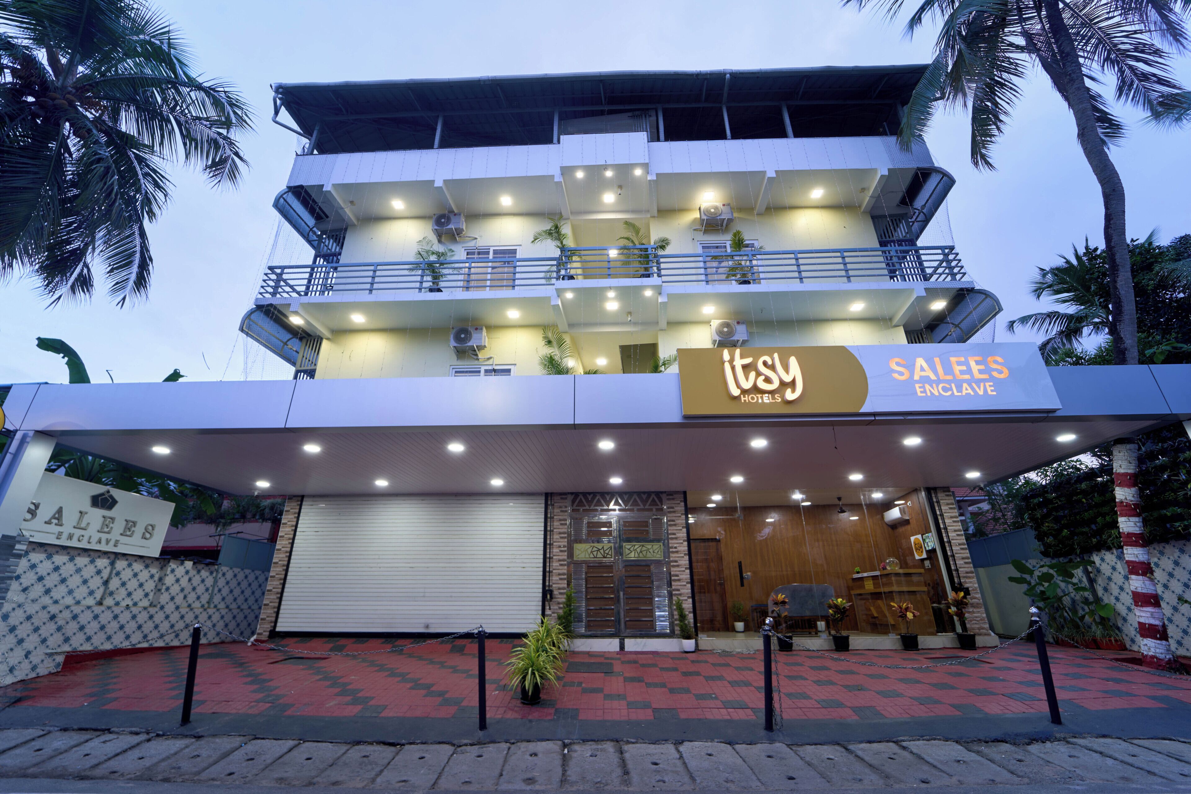 A multi-story hotel with balconies, air conditioning units, and a sign reading 'SALEES ENCLAVE.'