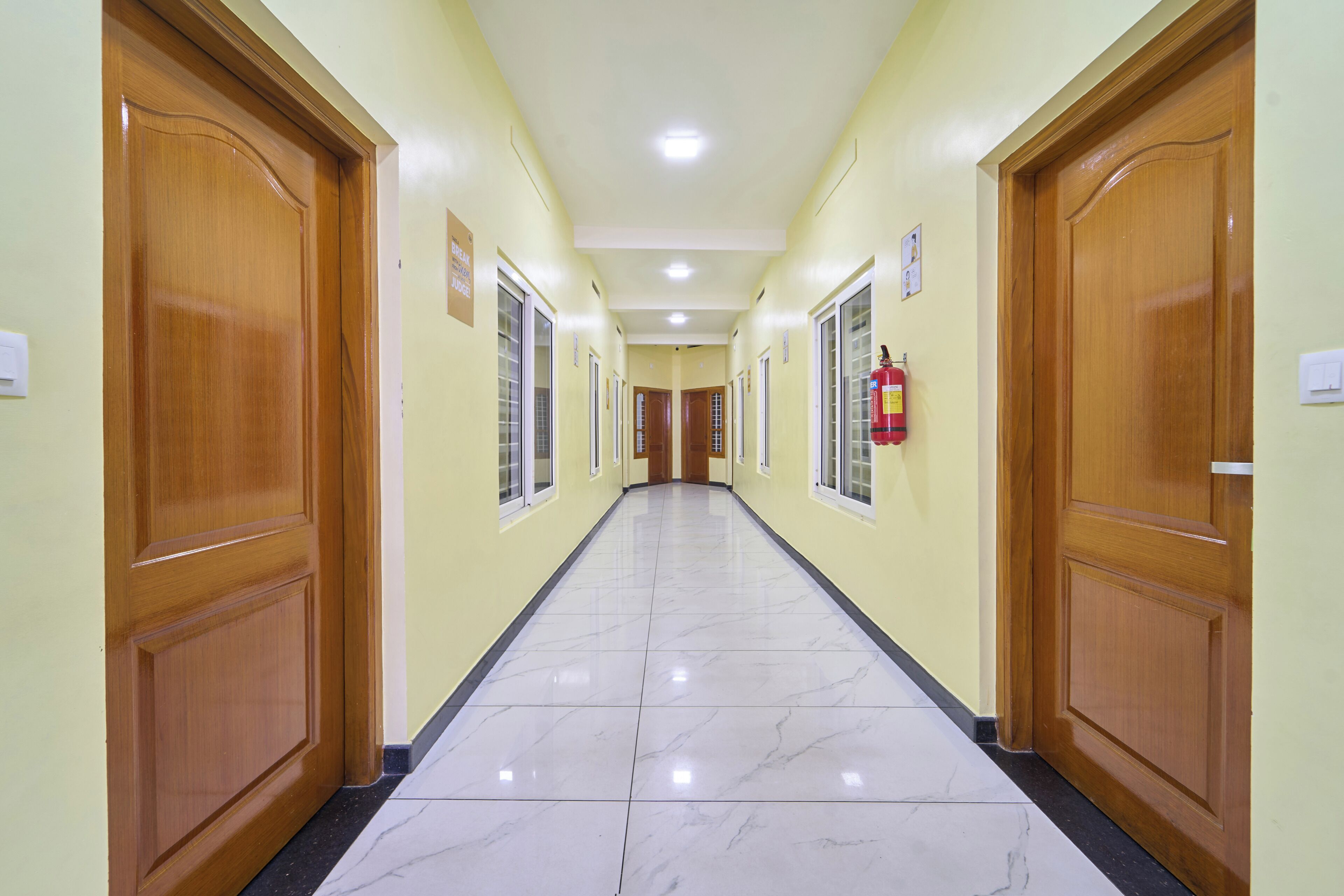 A hallway with wooden doors, a fire extinguisher, and a sign on the wall.