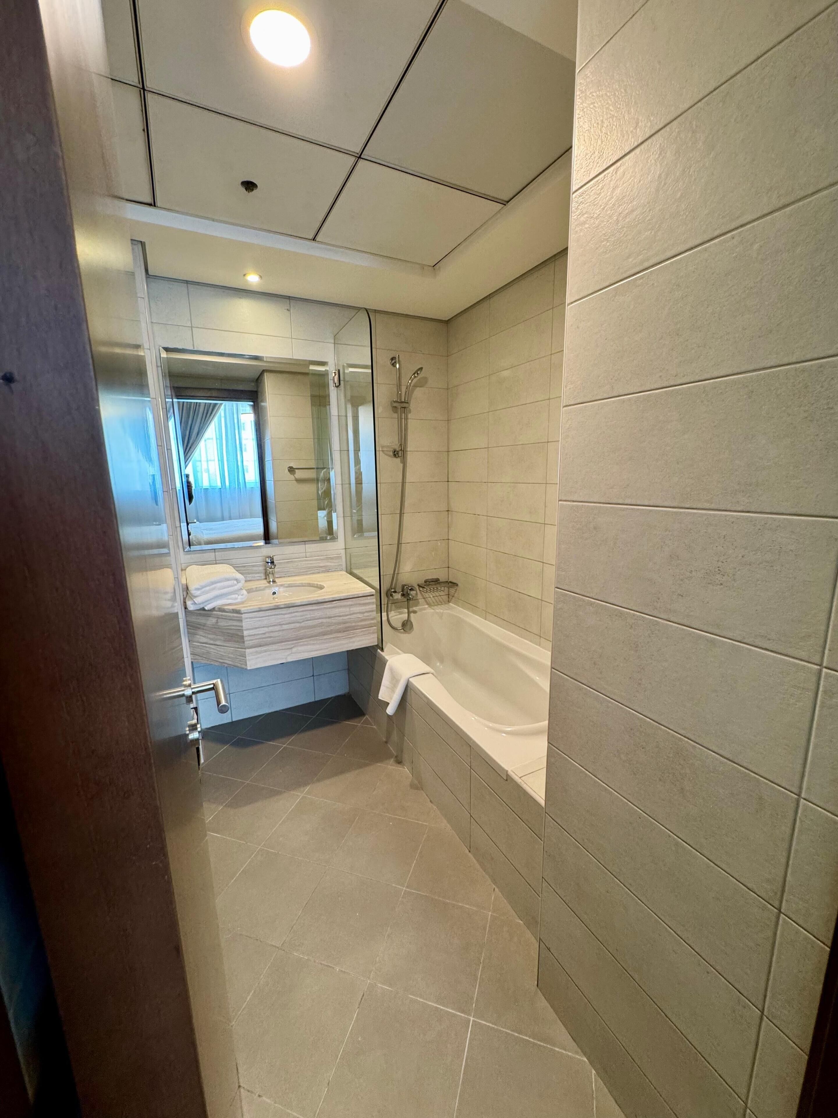 Un baño moderno con ducha envuelta en vidrio, bañera y tocador con espejo.
