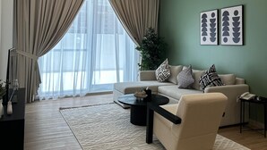 A modern living room with a sofa, coffee table, and a large window with curtains.