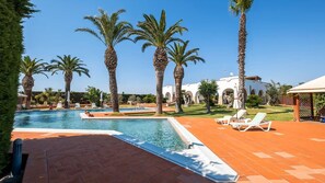 A pool area with palm trees, lounge chairs, and a building with arches. - Villa Ark Luxury Villa With Private Pool (Alliste)