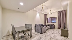 Ein modernes Wohnzimmer mit Esstisch, Sofas und einem Fernseher.