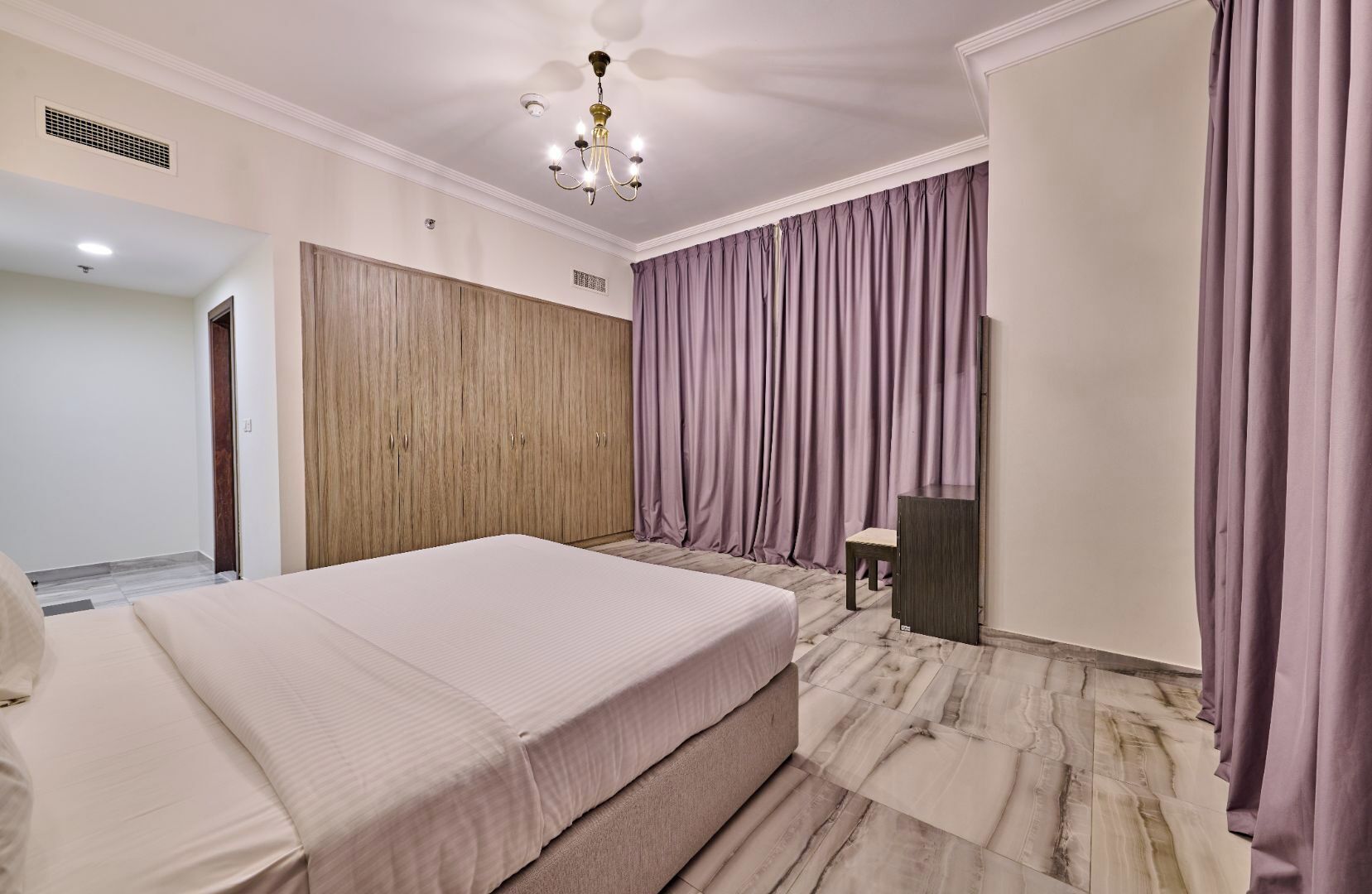 Una camera da letto con un letto grande, un'armadietto in legno, una scrivania e una sedia.