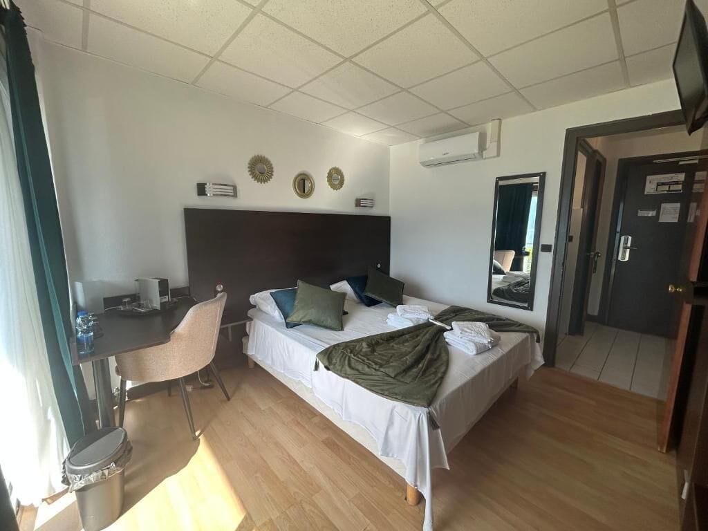 A hotel room with a bed, a desk, a chair, and a television.