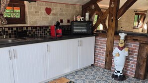 Eine Küche mit weißen Schränken, einer schwarzen Arbeitsplatte, einer roten Kaffeemaschine, einem schwarzen Elektrobackofen und einer Keramik-Kuh-Figur.