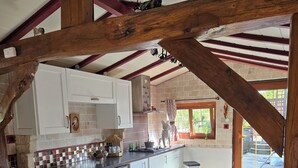 Eine rustikale Küche mit freiliegenden Holzbalken, weißen Schränken und einem Fliesenboden mit Muster.