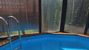 Ein Schwimmbecken mit Holzterrasse und Metallleiter.