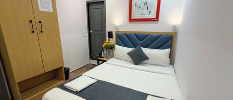 Une chambre d’hôtel avec un lit, une armoire, un tableau encadré au mur et une porte.