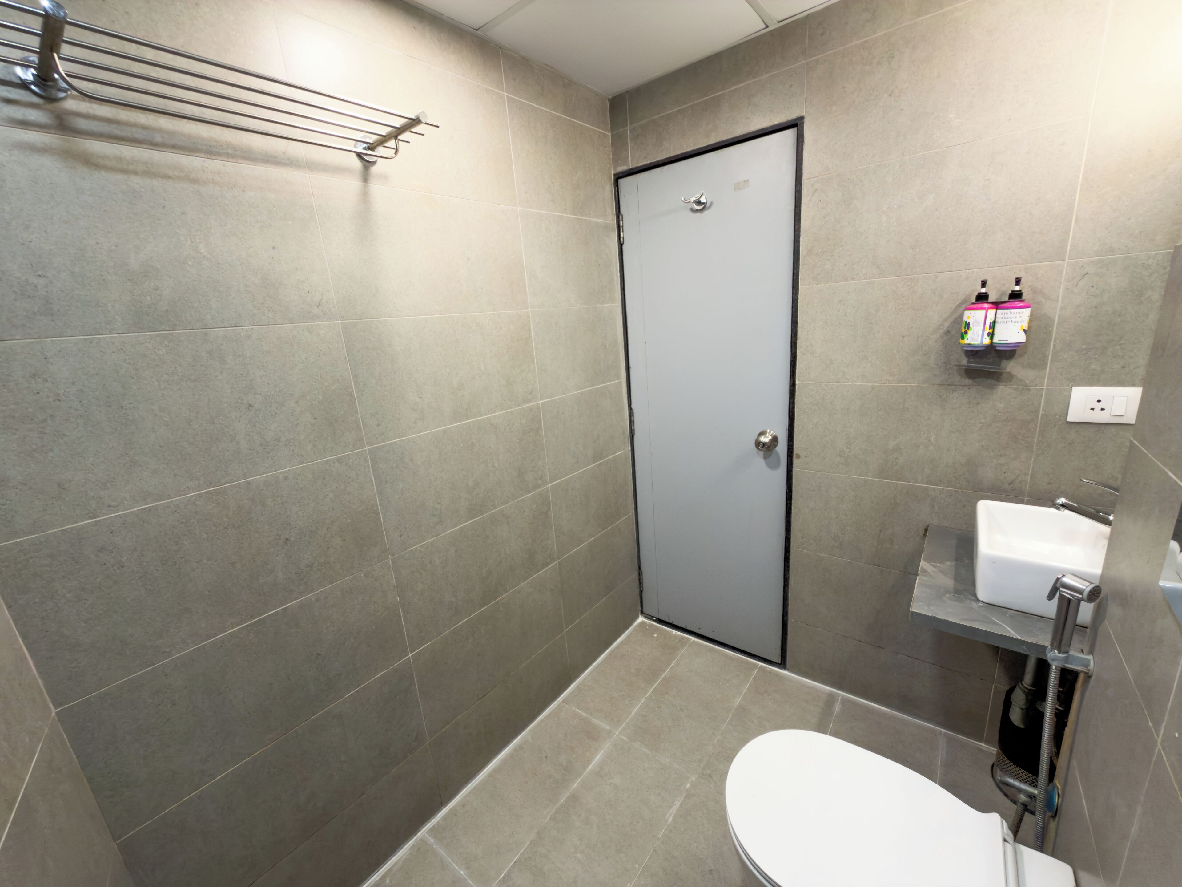 A bathroom with a shower, toilet, and a shelf with toiletries.