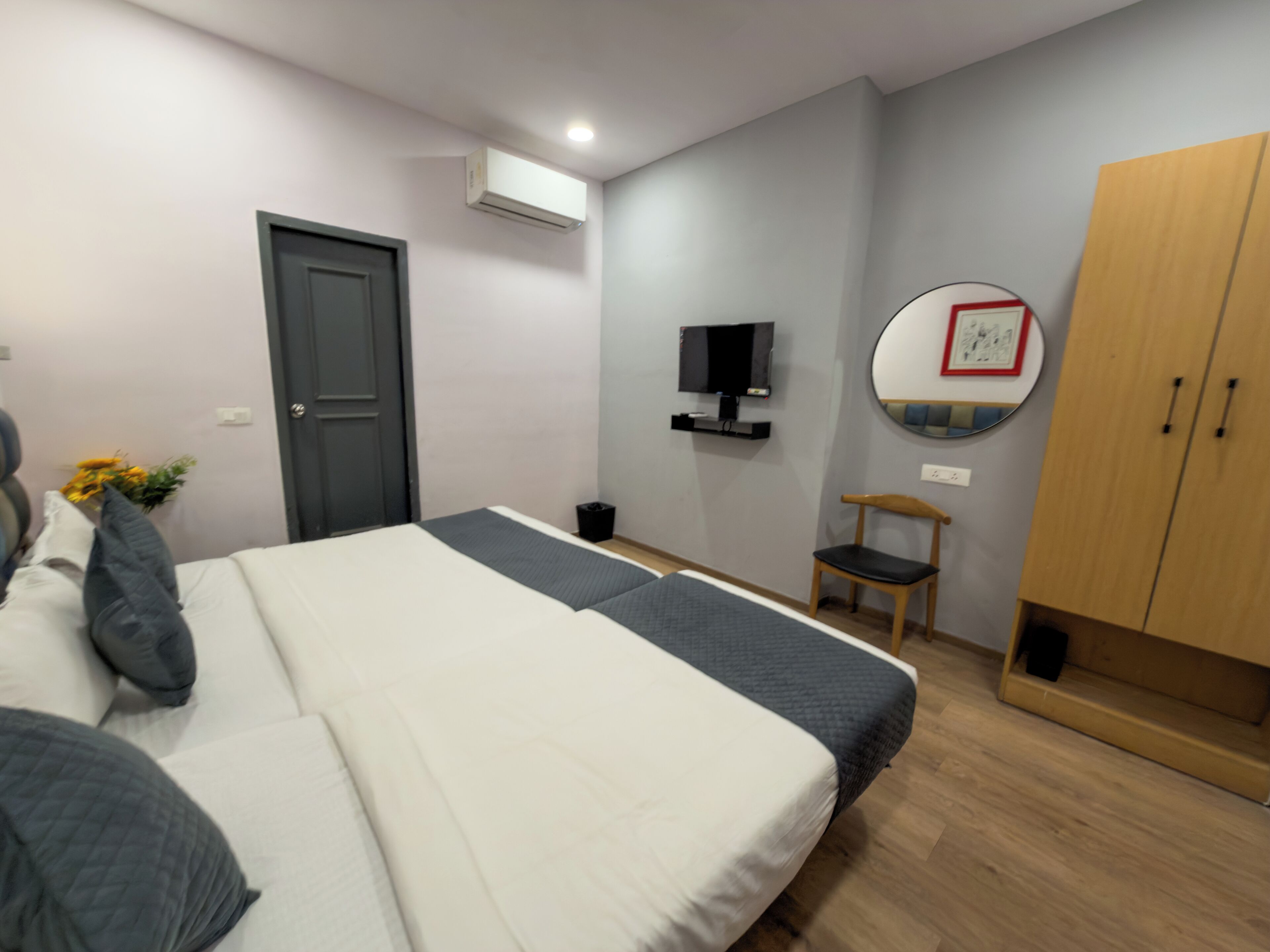A bedroom with a bed, a wardrobe, a television, and a mirror.