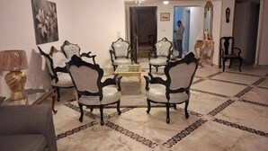 Un vaste salon doté d’un sol en marbre, d’une table basse centrale et de quatre fauteuils rembourrés aux motifs noir et blanc.