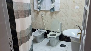 Une petite salle de bain équipée d’un bidet, de toilettes et d’un lavabo.