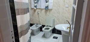 A small bathroom with a bidet, toilet, and sink. - Spacious 3-bedroom Apartment in Central Cairo With City View (Cairo)