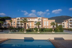 A hotel with a swimming pool, palm trees, and a mountain in the background. - Apartment 'Chez Mcvv' with Mountain View, Wi-Fi and Air Conditioning (Cavalaire-sur-Mer)