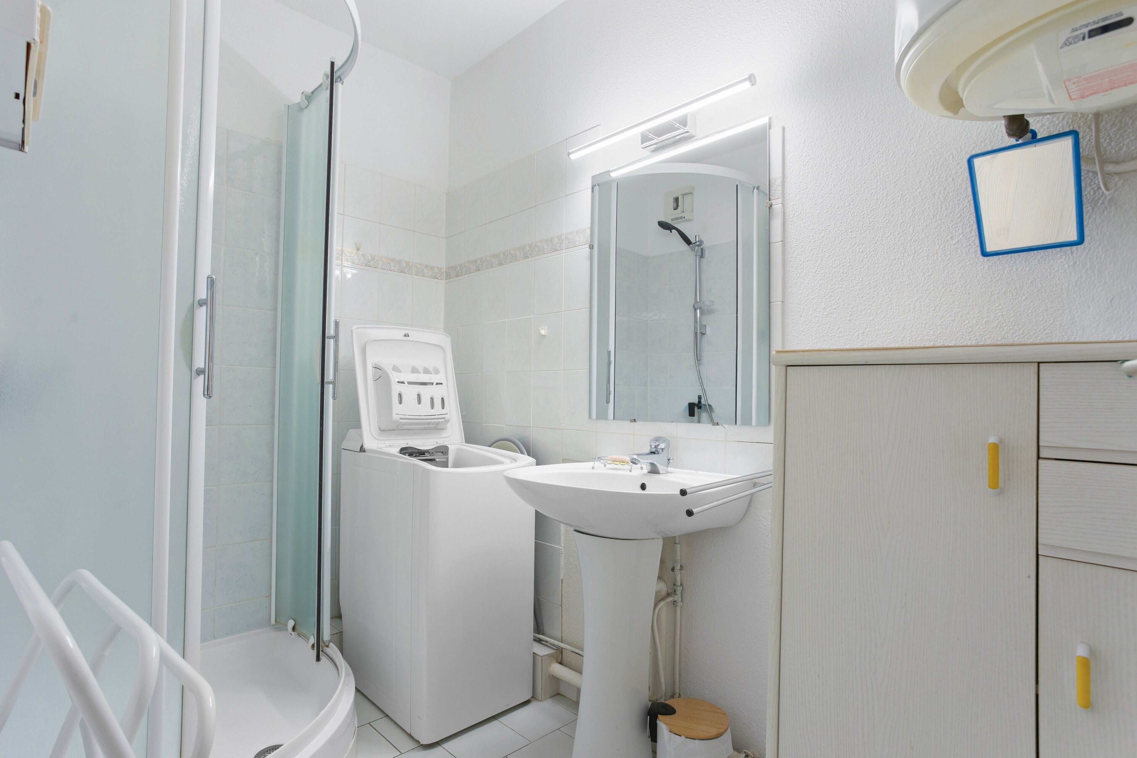 Un baño con ducha, lavamanos, espejo y mueble.