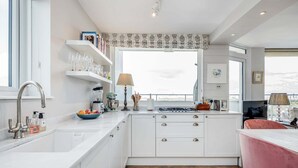 A modern kitchen with white cabinetry, a large window, and a view of the city. - AVAL Lovely 2-bed flat with balcony in Notting Hill, West London (London)