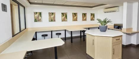 Una cocina moderna con una isla central, taburetes de bar y una planta en maceta.