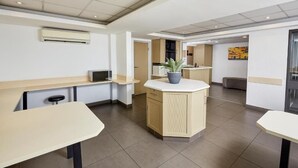 A modern kitchen with a central island, built-in appliances, and a seating area with a potted plant. - SUN1 Parow Cape Town (Cape Town)