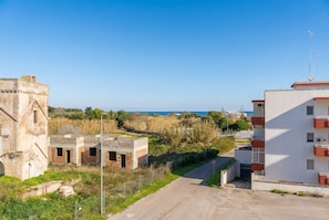 A coastal area with a mix of modern and historical buildings, a clear road, and a view of the sea. - Circe Sea View Apartment Otranto – Charming Studio with Terrace, Wi-Fi & AC (Otranto)