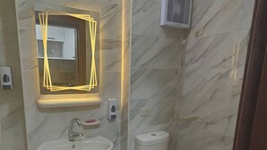 Um banheiro moderno com parede de mármore, pia de pedestal, vaso sanitário e purificador de ar fixado na parede.
