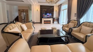 Un amplio salón con chimenea, sofás de cuero, una mesa de centro y una araña.