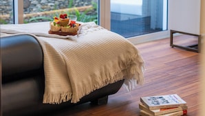 Un dormitorio con una cama, una bandeja de fruta y una pila de libros en el suelo.