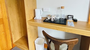 A compact room with a wooden desk, a chair, a coffee maker, a Wi-Fi sign, and a mirror. - Tinnies Guest House (Valentia Island)