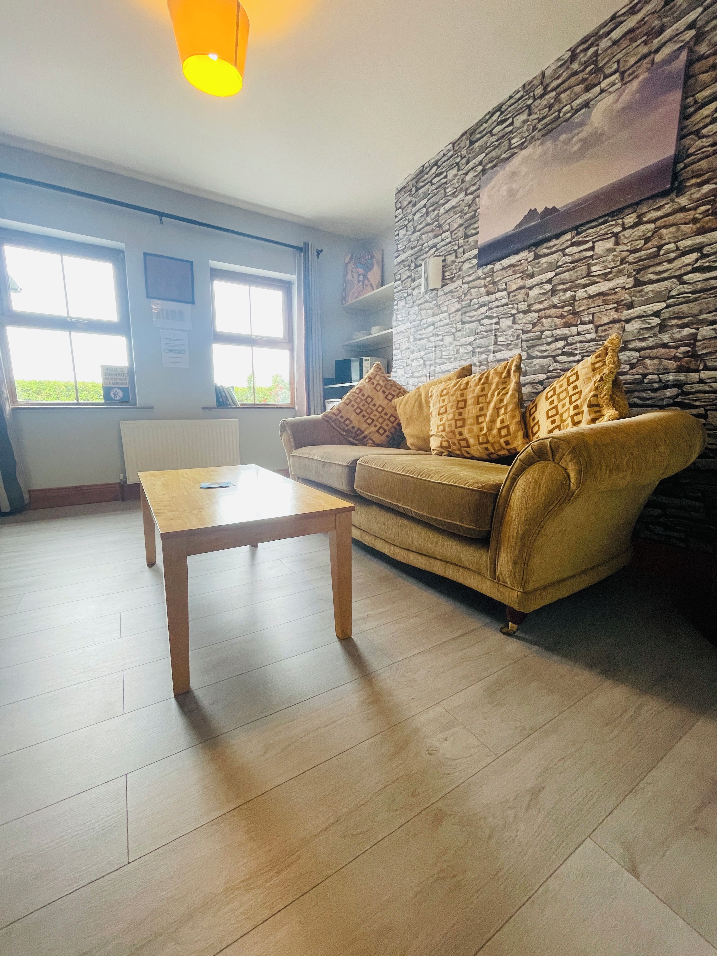 Un salon avec un canapé, une table basse et un mur en pierre.