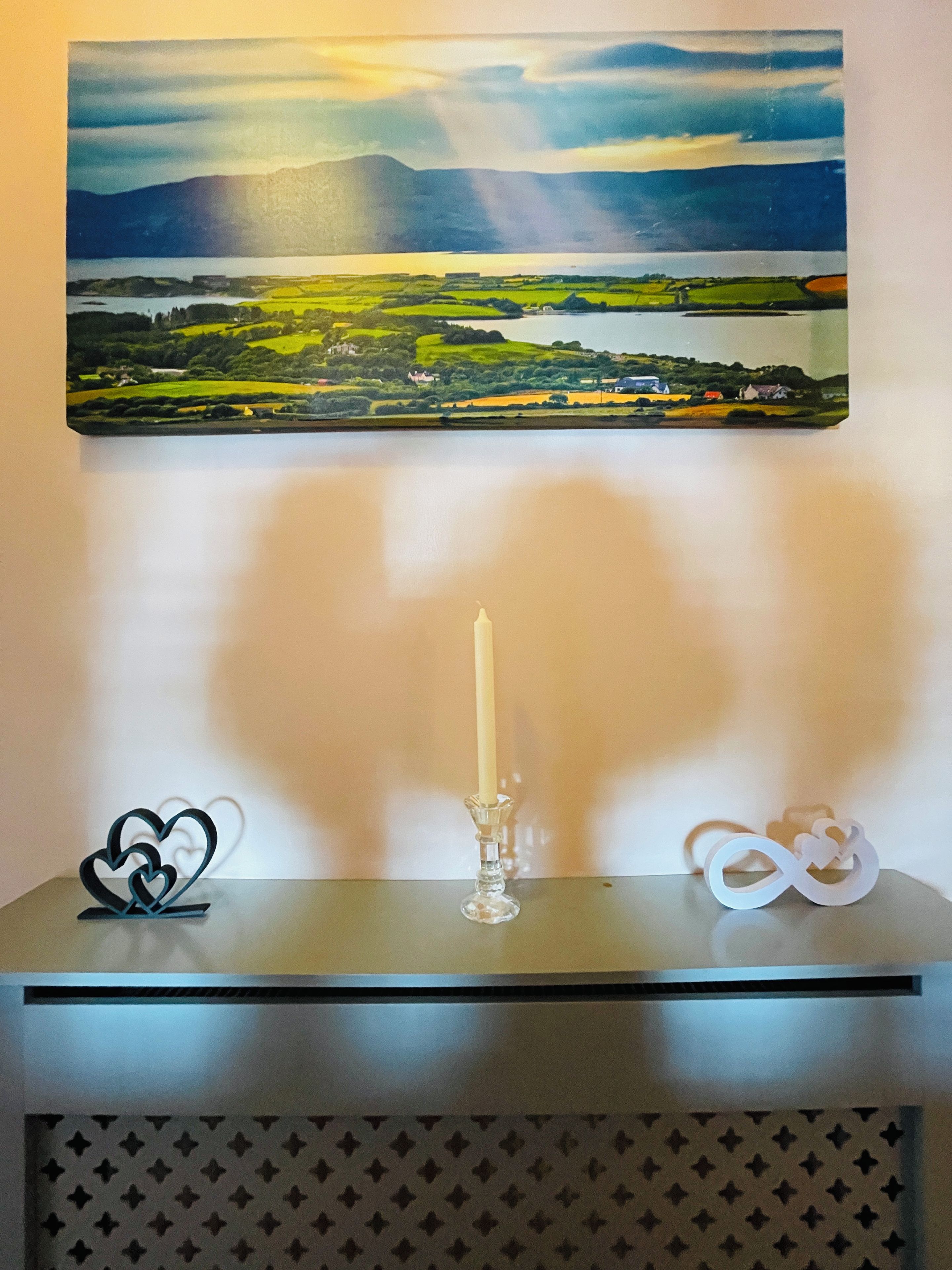 Una mesa con una vela, un objeto con forma de corazón y un símbolo de infinito.