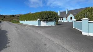 A gated driveway leading to a building with a sign that reads 'Timeless Guest House.' - Tinnies Guest House (Valentia Island)