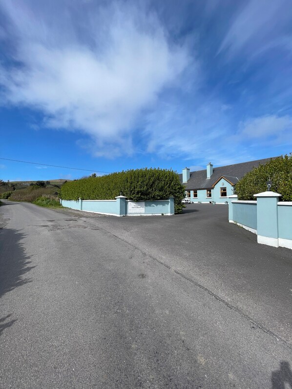 A gated driveway leading to a building with a sign that reads 'Timeless Guest House.' - Tinnies Guest House (Valentia Island)