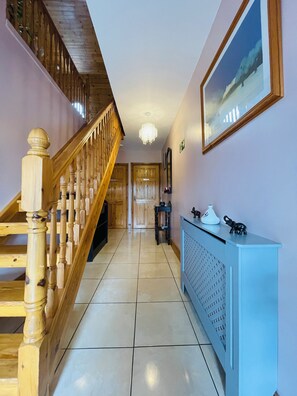 A hallway with a wooden staircase, a radiator, and a framed picture on the wall. - Tinnies Guest House (Valentia Island)