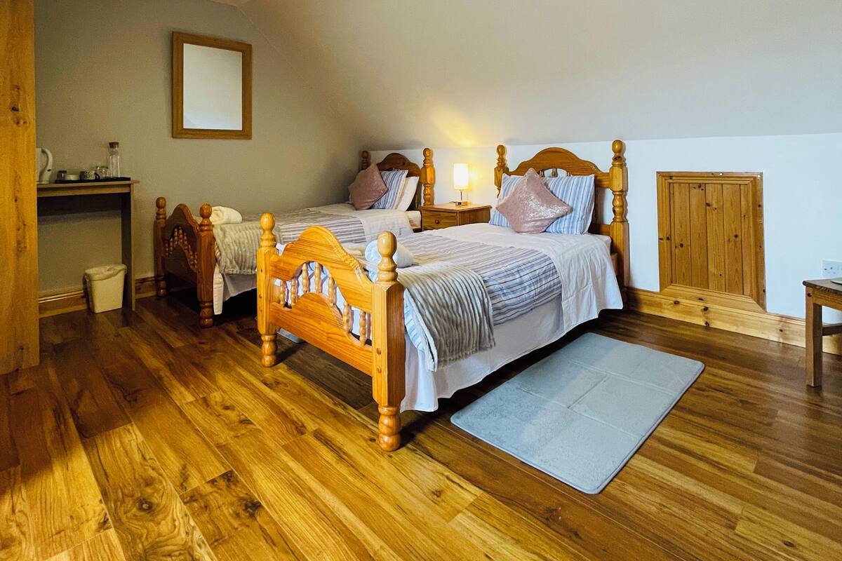 A bedroom with a wooden bed, bedside tables, a nightstand, a mirror, and a wooden wardrobe.