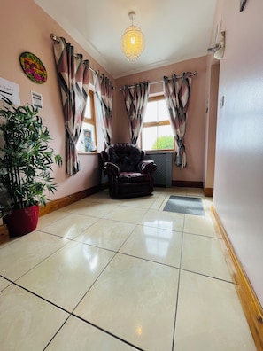 Een kamer met een grote potplant, een leren fauteuil en een kroonluchter.