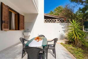 A patio with a table and chairs, a bottle, and a pineapple on the table. - Casa Amanda in Torre dell'Orso with Private Garden, Wi-Fi, and Air Conditioning (Torre dell'Orso)