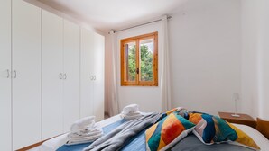 Een slaapkamer met een bed, een kledingkast, een raam met uitzicht en een nachtkastje.