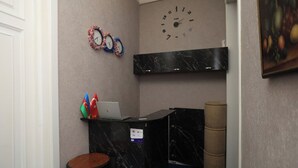 Una zona de recepció amb un taulell de marbre, un rellotge i banderes a la paret.