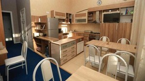 Una cuina compacta amb armaris de fusta, un frigorífic, un microones i una zona de menjador amb cadires i taula.