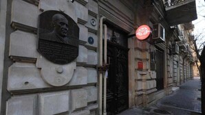 Façana d'edifici amb una placa i una porta.