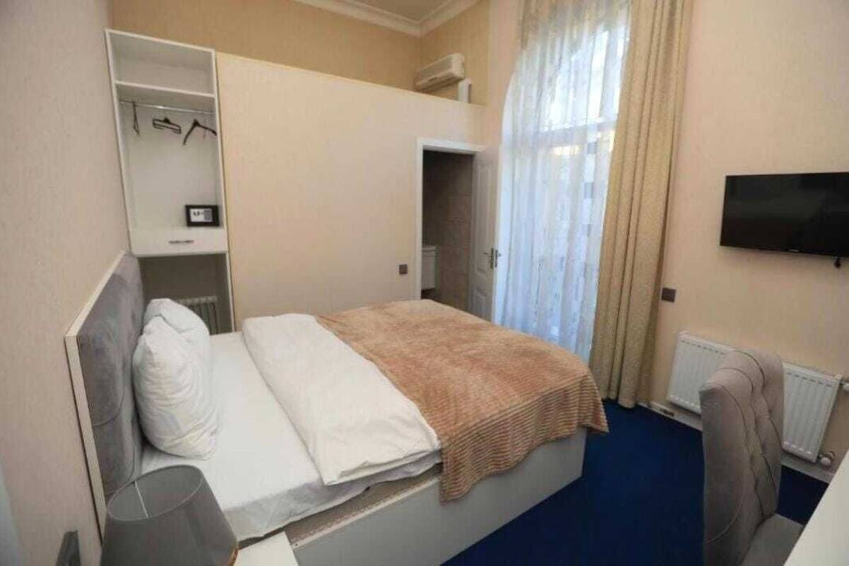 Ein Hotelzimmer mit Bett, Kleiderschrank, Fernseher und einem Fenster mit Vorhängen.