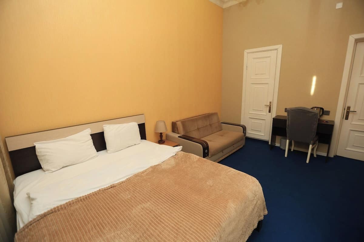 Ein Hotelzimmer mit Bett, Sofa, Schreibtisch und Stuhl.