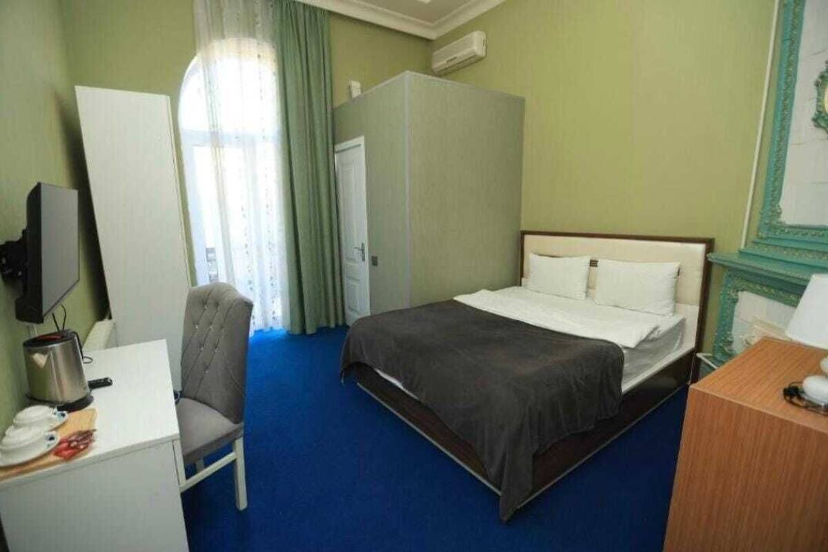 Ein Hotelzimmer mit Bett, Schreibtisch mit Stuhl, Kleiderschrank und Fernseher.