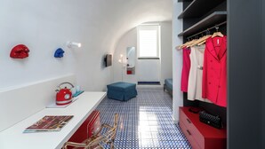 A modern room with a white wall, a red kettle, a blue chair, a red coat rack, and a blue patterned floor. - Domus Pio XI (Sant'Agnello)
