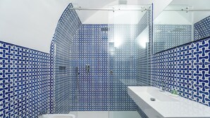 A bathroom with blue patterned tiles, a white sink, and a glass shower enclosure. - Domus Pio XI (Sant'Agnello)