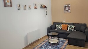 A living room with a dark grey sofa, a round coffee table, and a patterned rug. - Large 47 m² renovated family apartment on 1st floor - Portes des Ardennes (Charleville-Mézières)