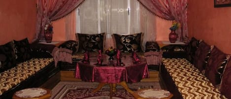 A traditional room with a sofa set, a dining table, and a chandelier.